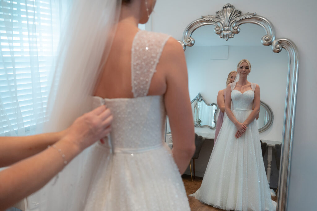 Wedding dress being zipped up by her mum.